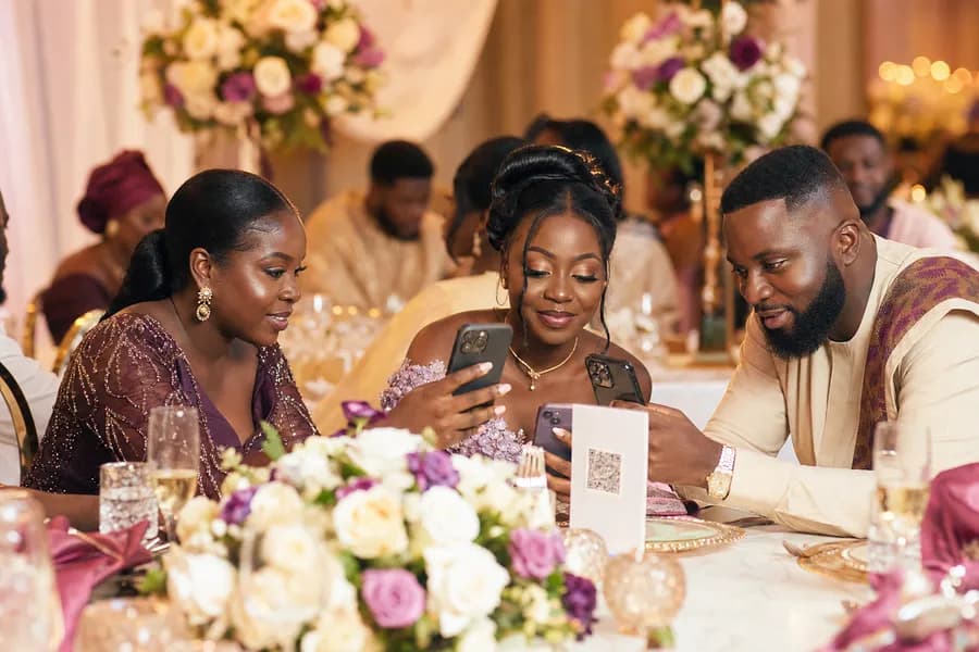 Guests sharing photos from the table at an African wedding